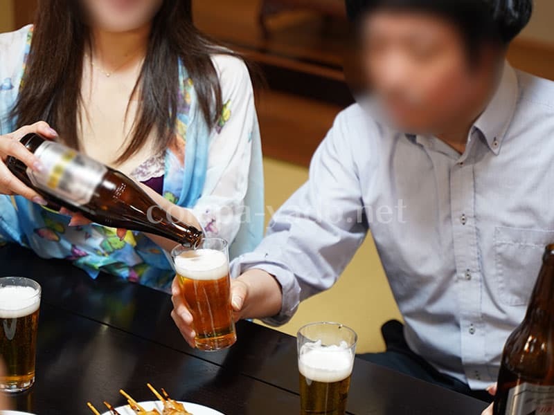 男性に水色の浴衣を着たコンパニオンがビールをお酌する